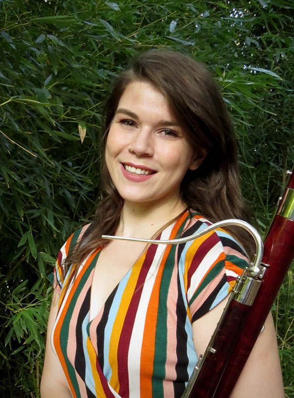 Woman holding a bassoon and smiling at the camera